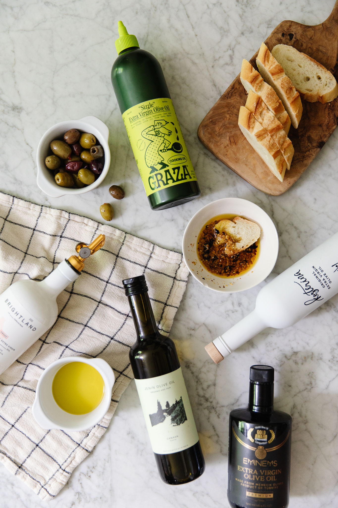Chris Loves Julia | Flatlay of olive oil bottles, olives, dipping oils and sliced bread