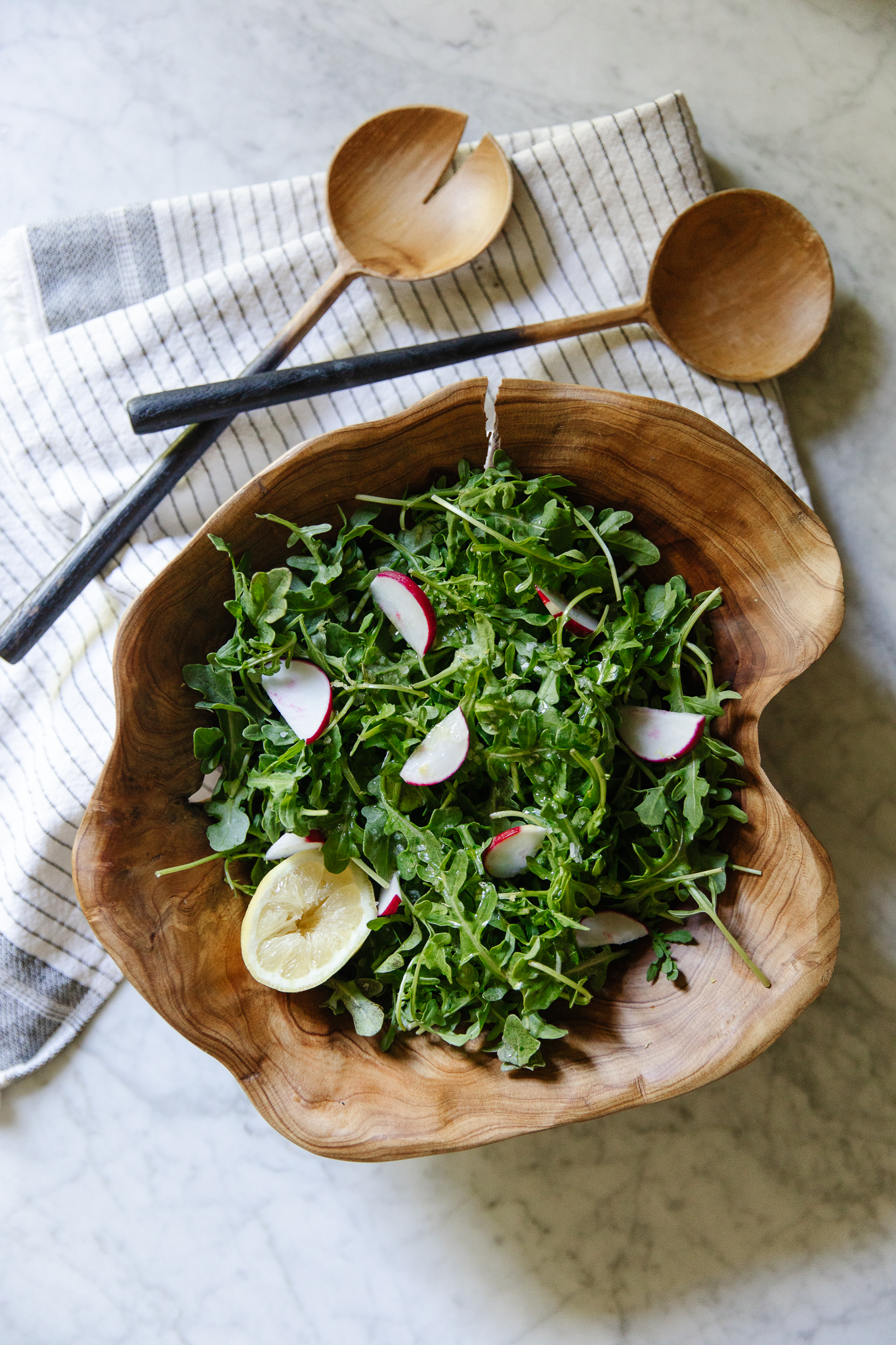 Chris Loves Julia | Wooden bowl filled with arugula, sliced radishes and a half lemon