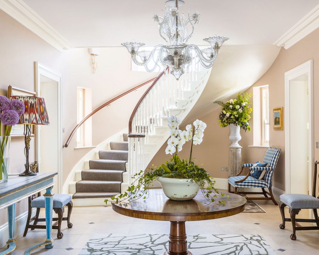 Foyer with a curved staircase, chandelier, and seating area.