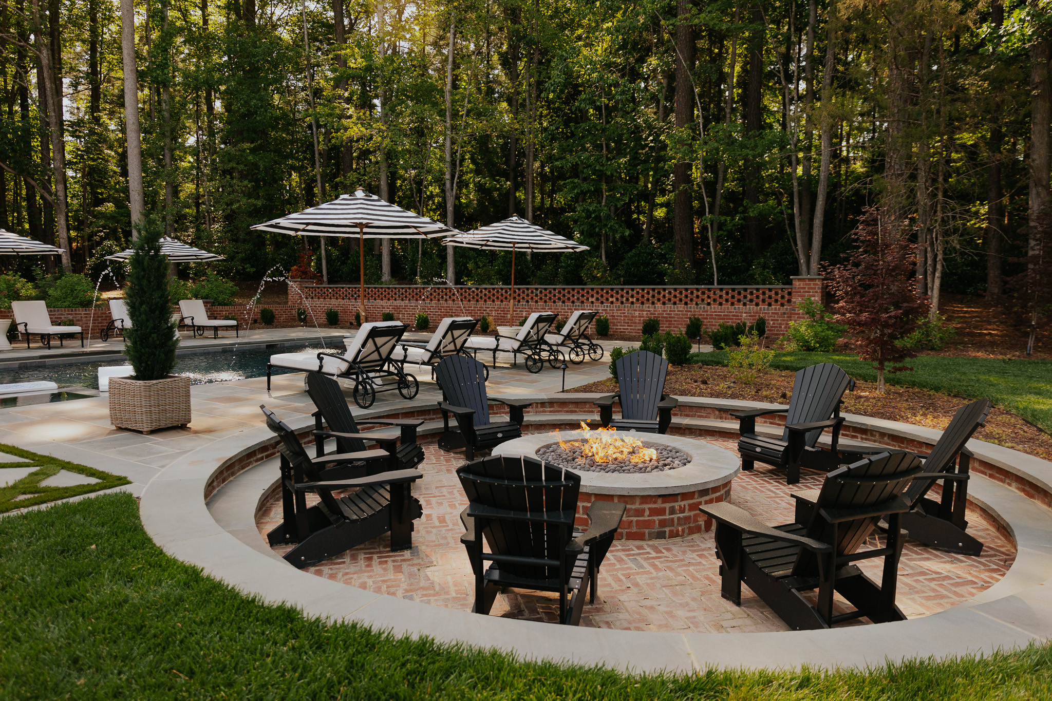 Fire pit outdoors surrounded by black adirondack chairs