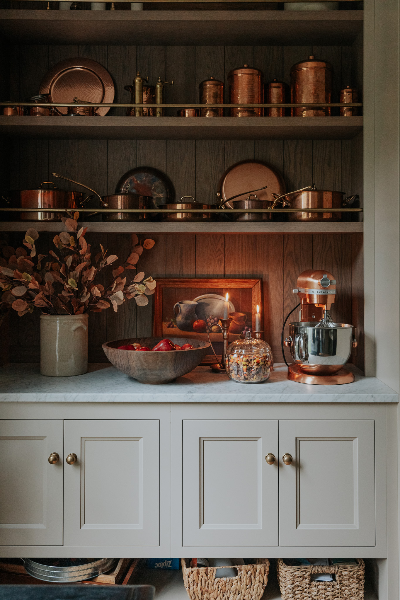 Chris Loves Julia | Copper pots on kitchen shelves, two brass candlesticks, and a glass pumpkin filled with candy corn mix.