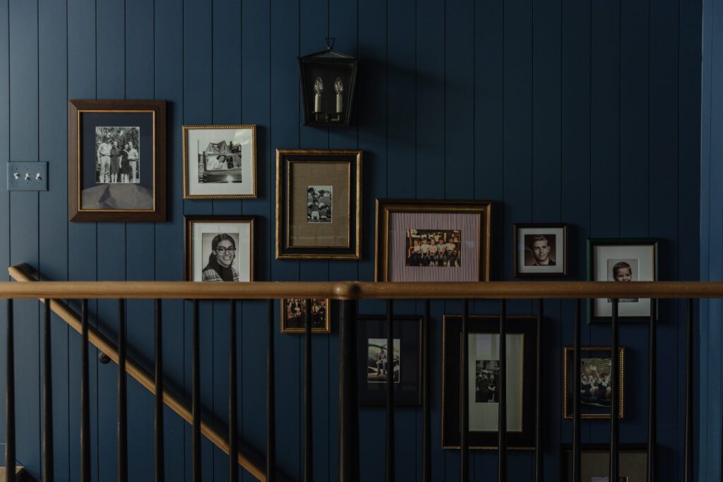 A dark staircase with a staggered gallery of Framebridge-framed old photos on the wall