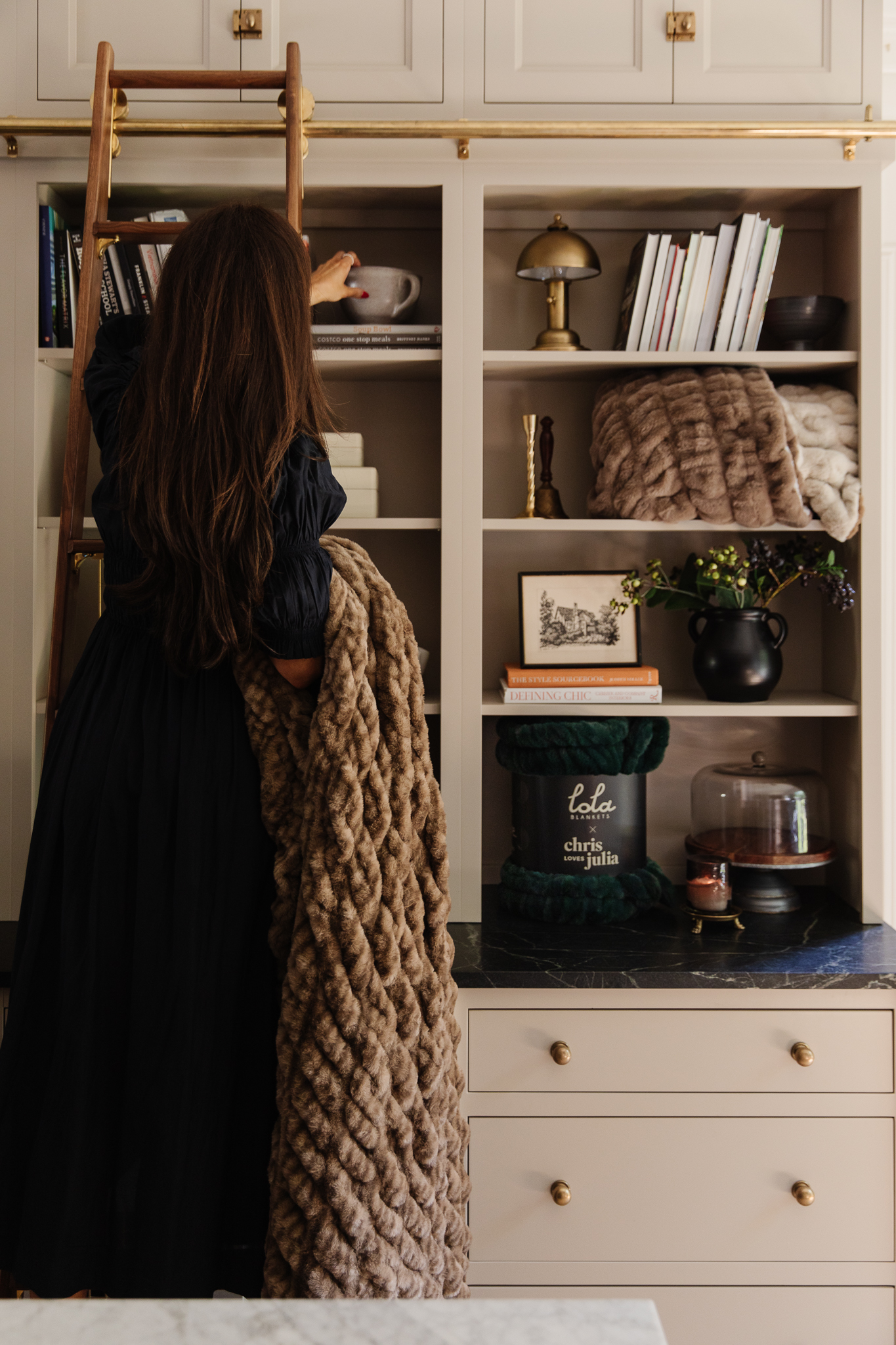 Chris Loves Julia | Julia standing on the library ladder holding a new CLJ x Lola Blanket in color Corduroy
