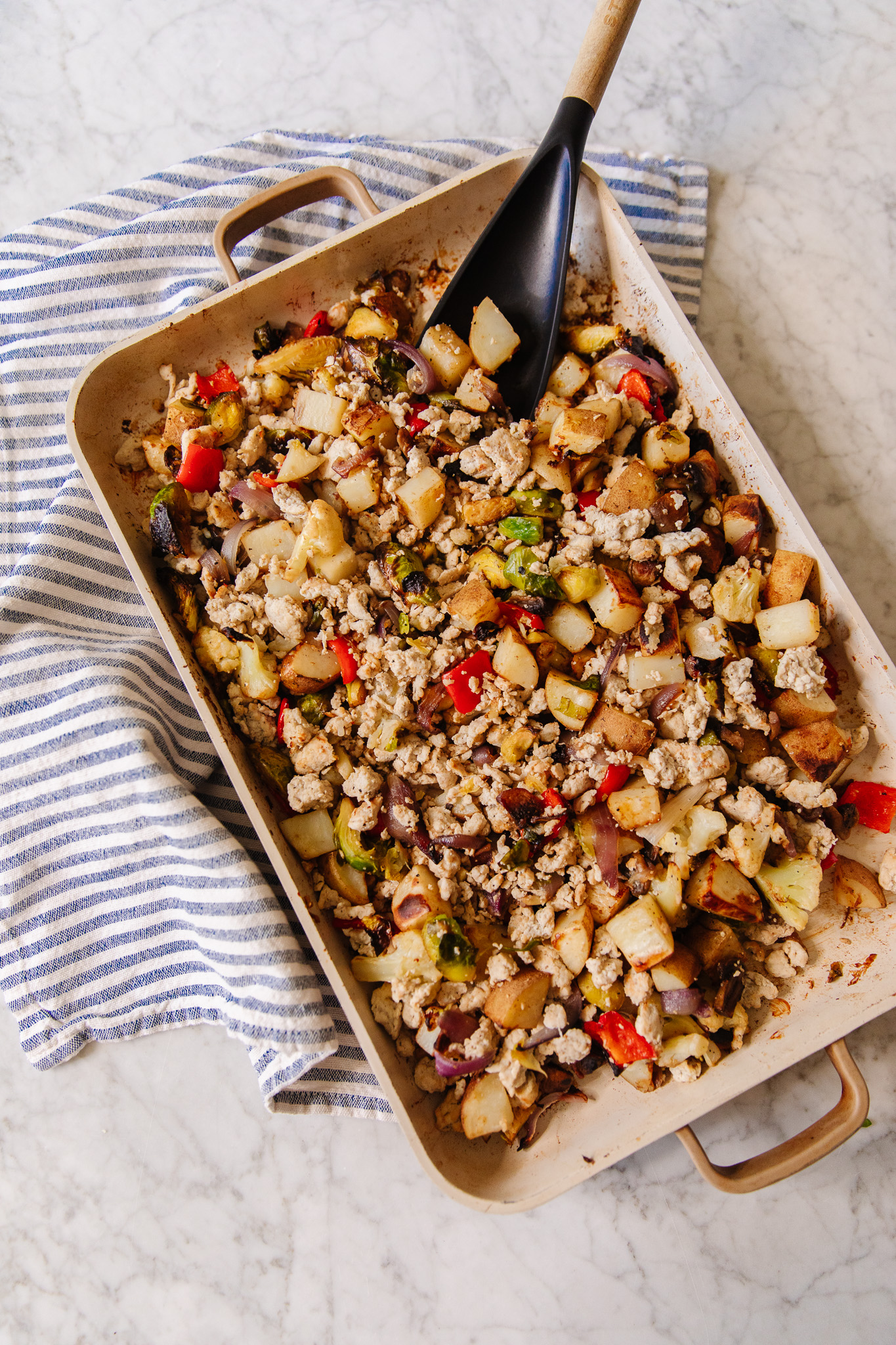 An Our Place roasting pan with breakfast hash of potatoes, cauliflower, chicken sausage, and red peppers