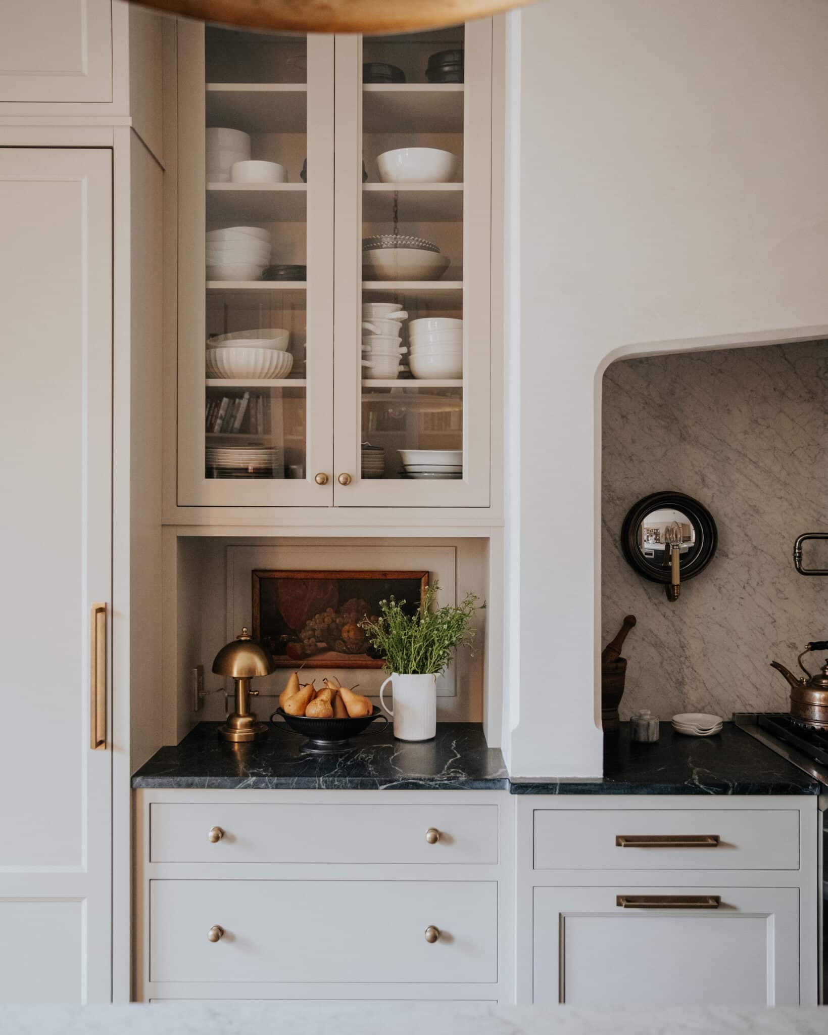 Kitchen cabinets with glass fronts overhead and a black soapstone countertop