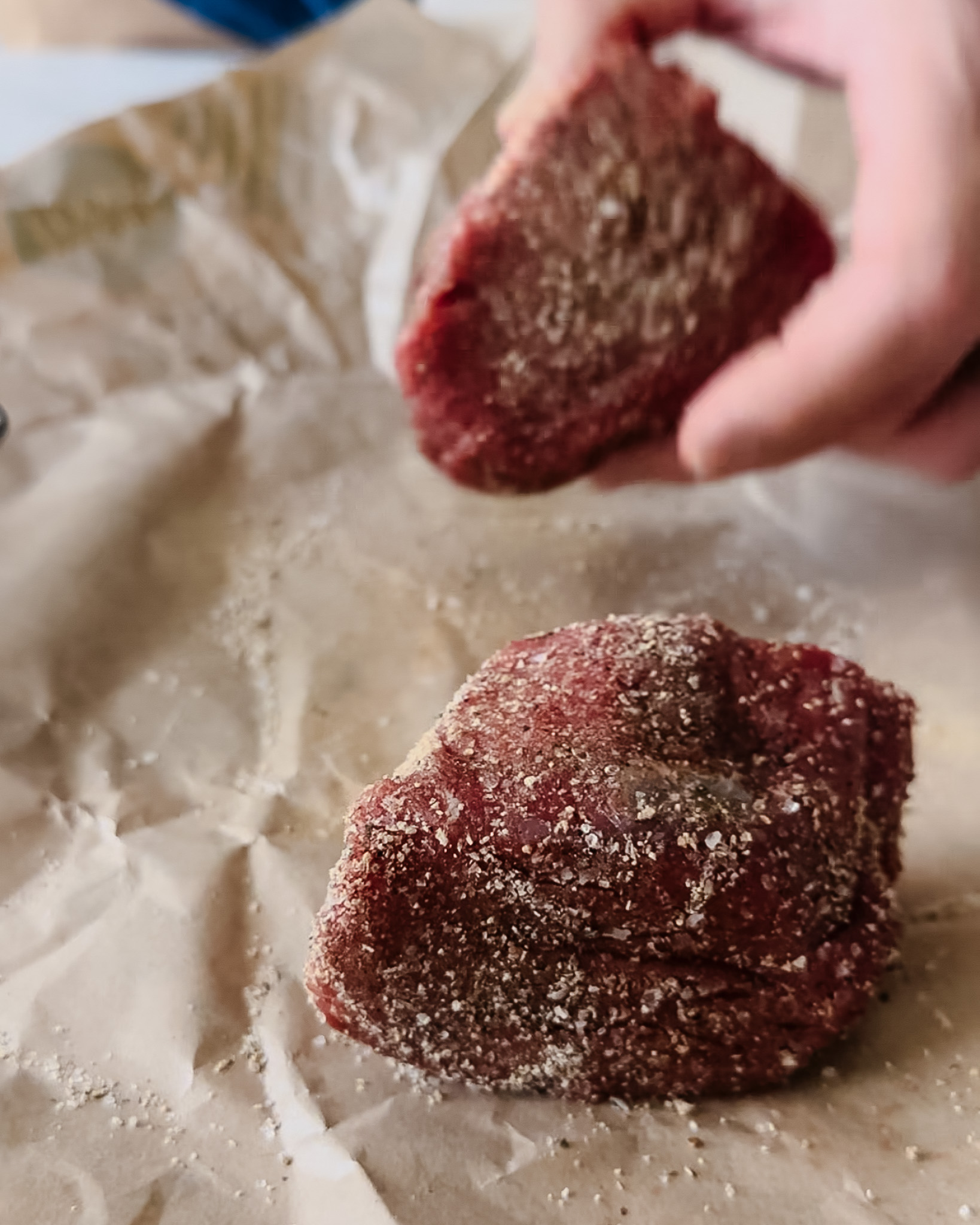 Adding seasoning blend to raw filet mignon steaks