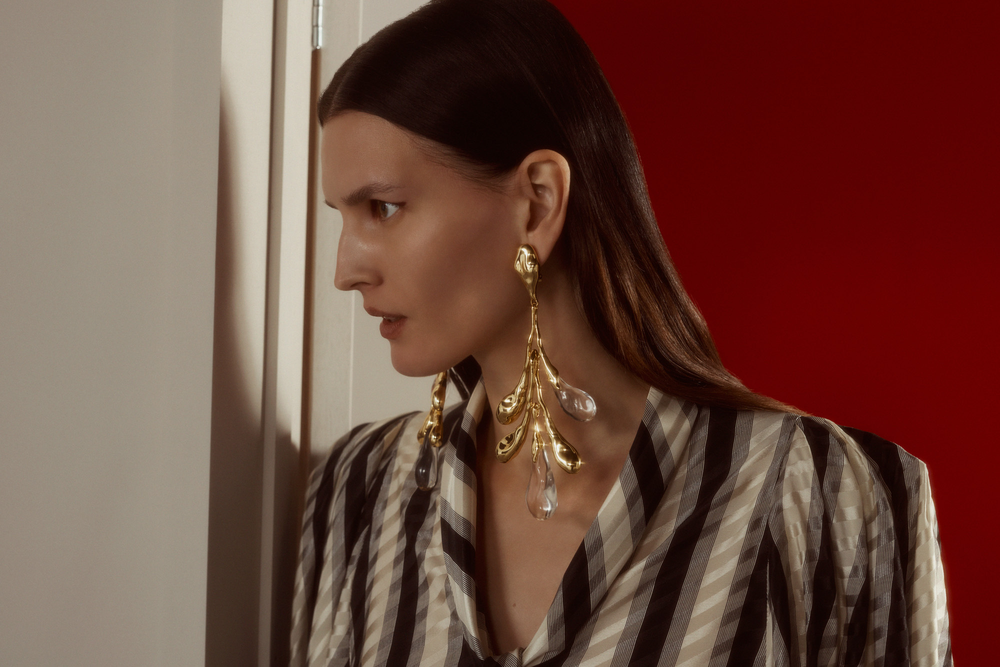 Model in colourful, eclectic outfit walks through a door to a red room wearing looks from the S/S 2025 season