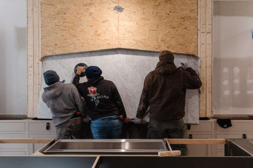 A few guys installing the marble backsplash behind the range