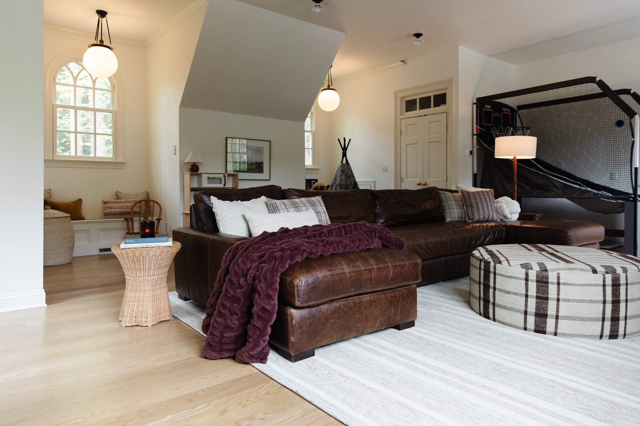 The playroom with a large leather couch and plaid ottoman
