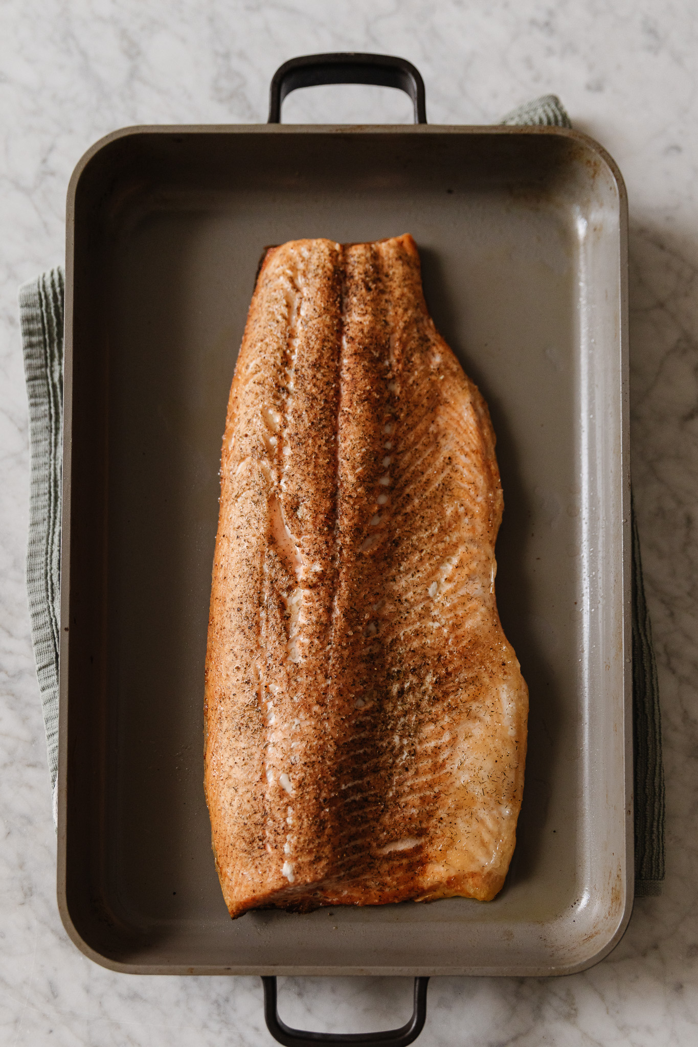 A whole filet of salmon roasted in a roasting pan