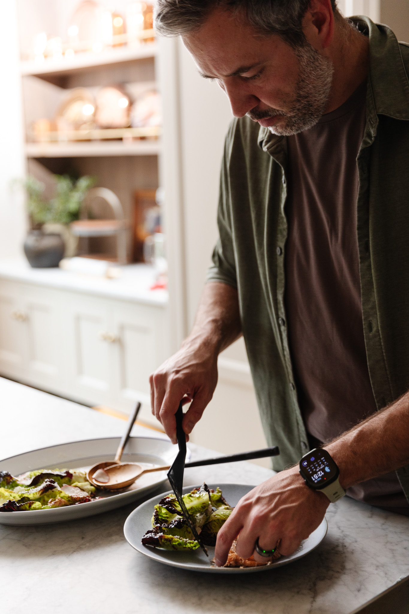 Chris serving salmon on a plate next to a baby gem lettuce salad