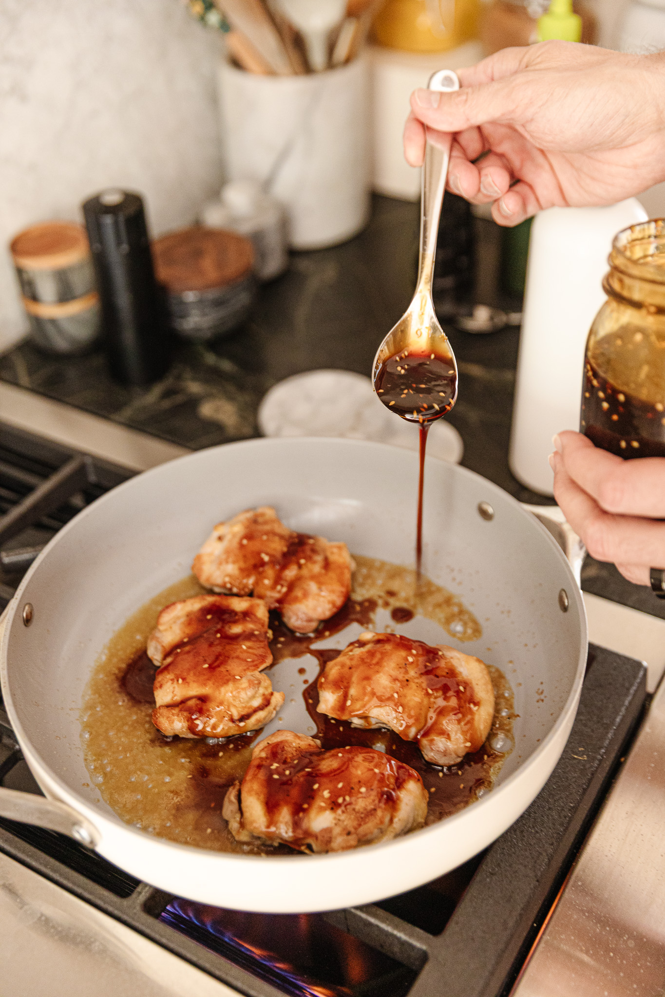Drizzling teriyaki sauce over chicken in a saute pan