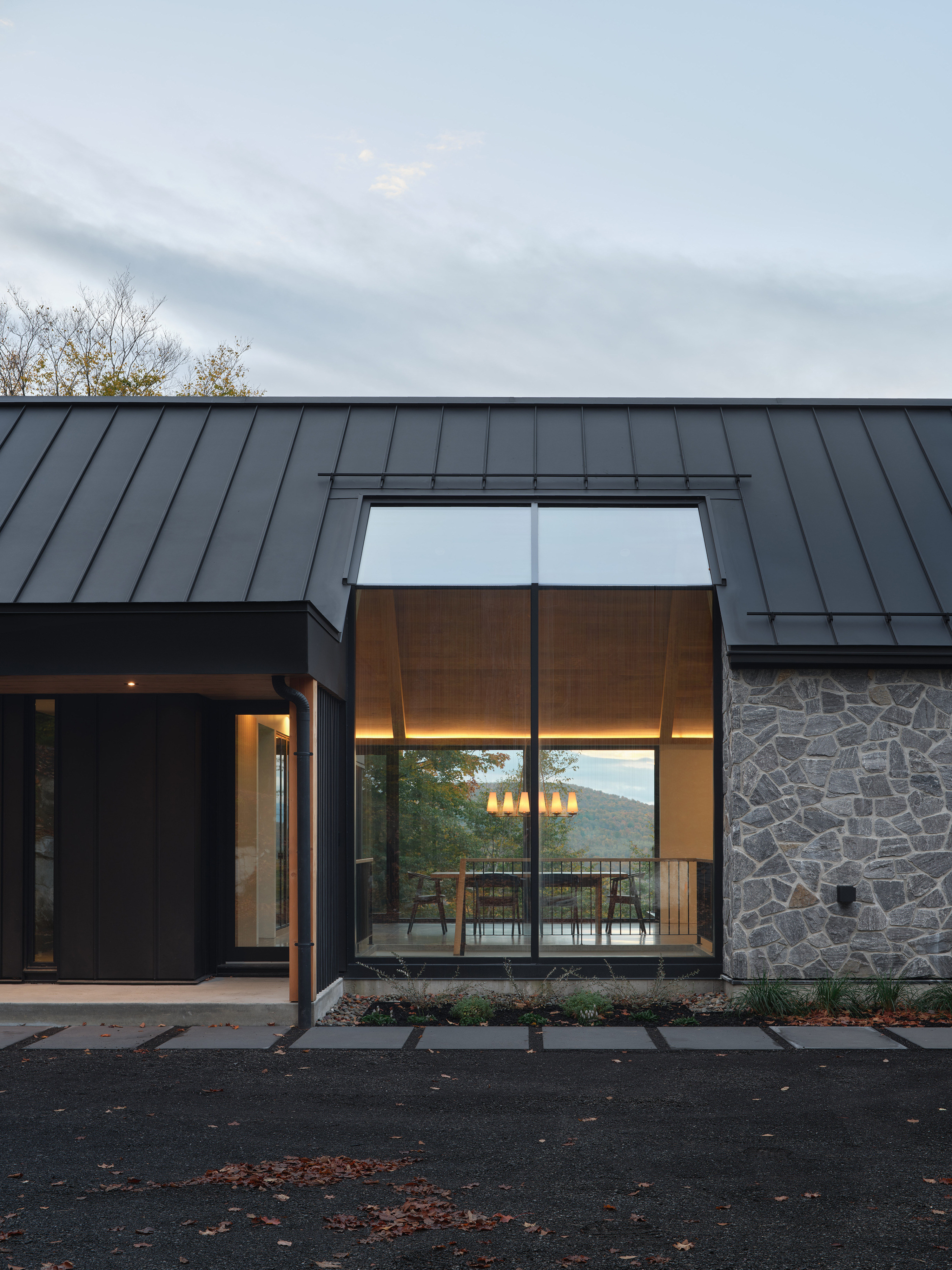 The entrance porch is set alongside a window that reveals the landscape through the structure