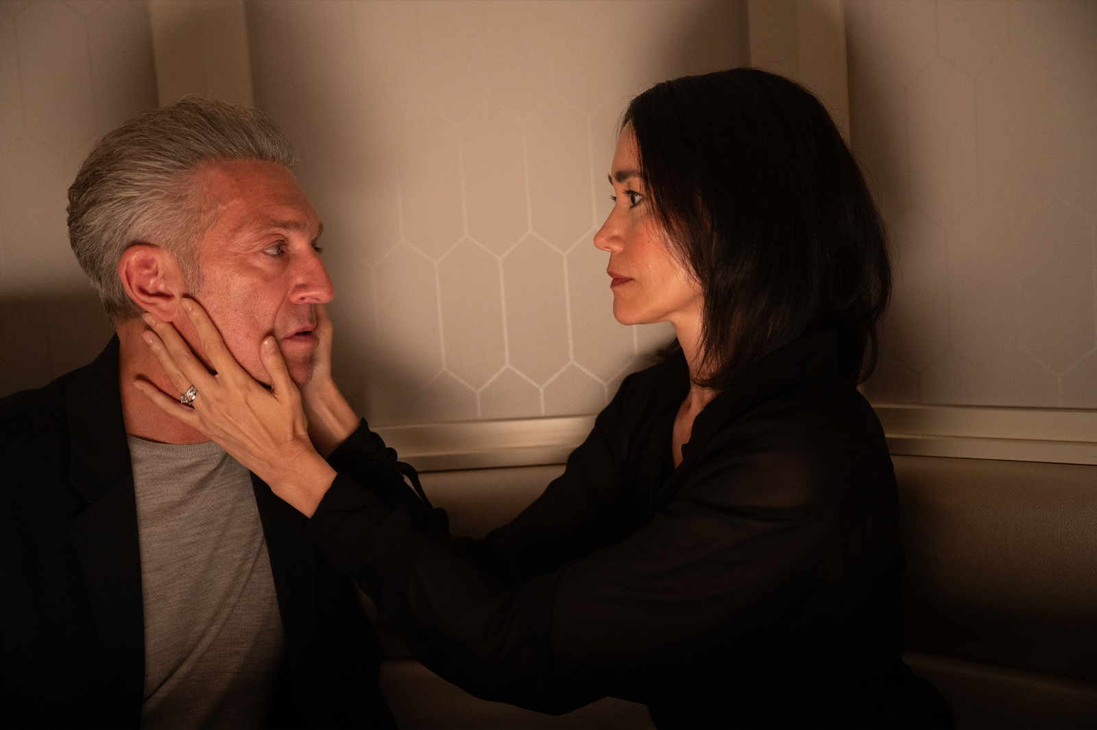 Film still from The Shrouds showing man facing woman, her hands on his face