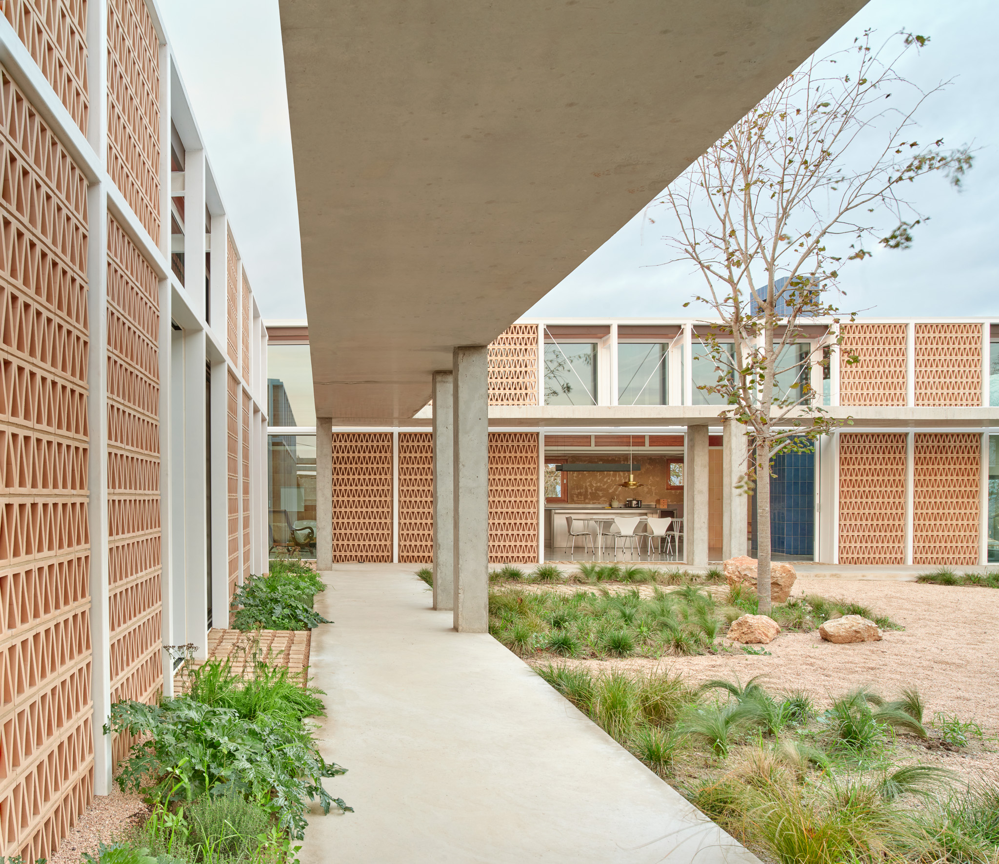 The plot is threaded with covered walkways in concrete, juxtaposed with the tiled screen walls of the pavilions