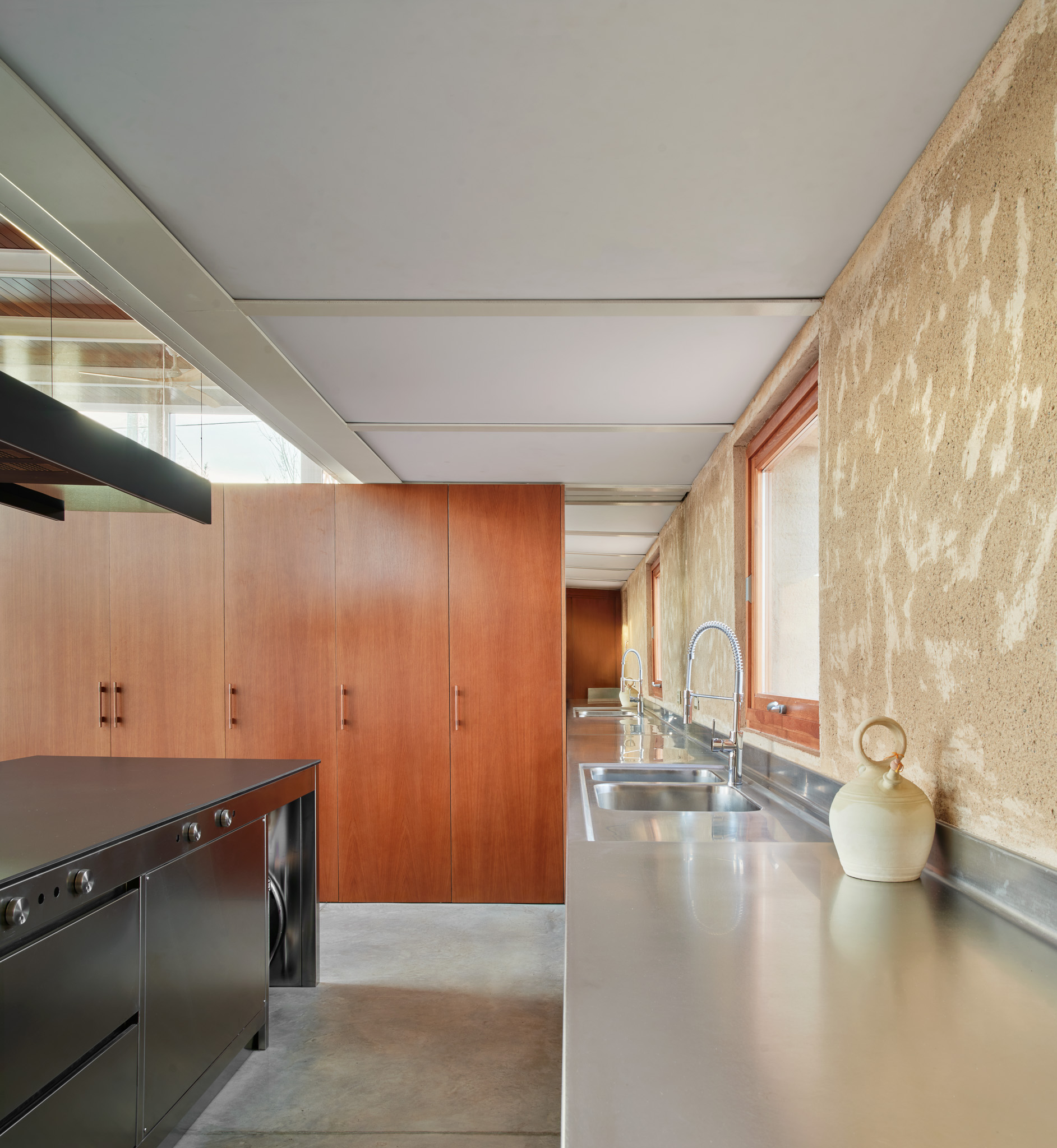 The kitchen, showing the roughly finished external walls alongside Iroko wood cabinetry