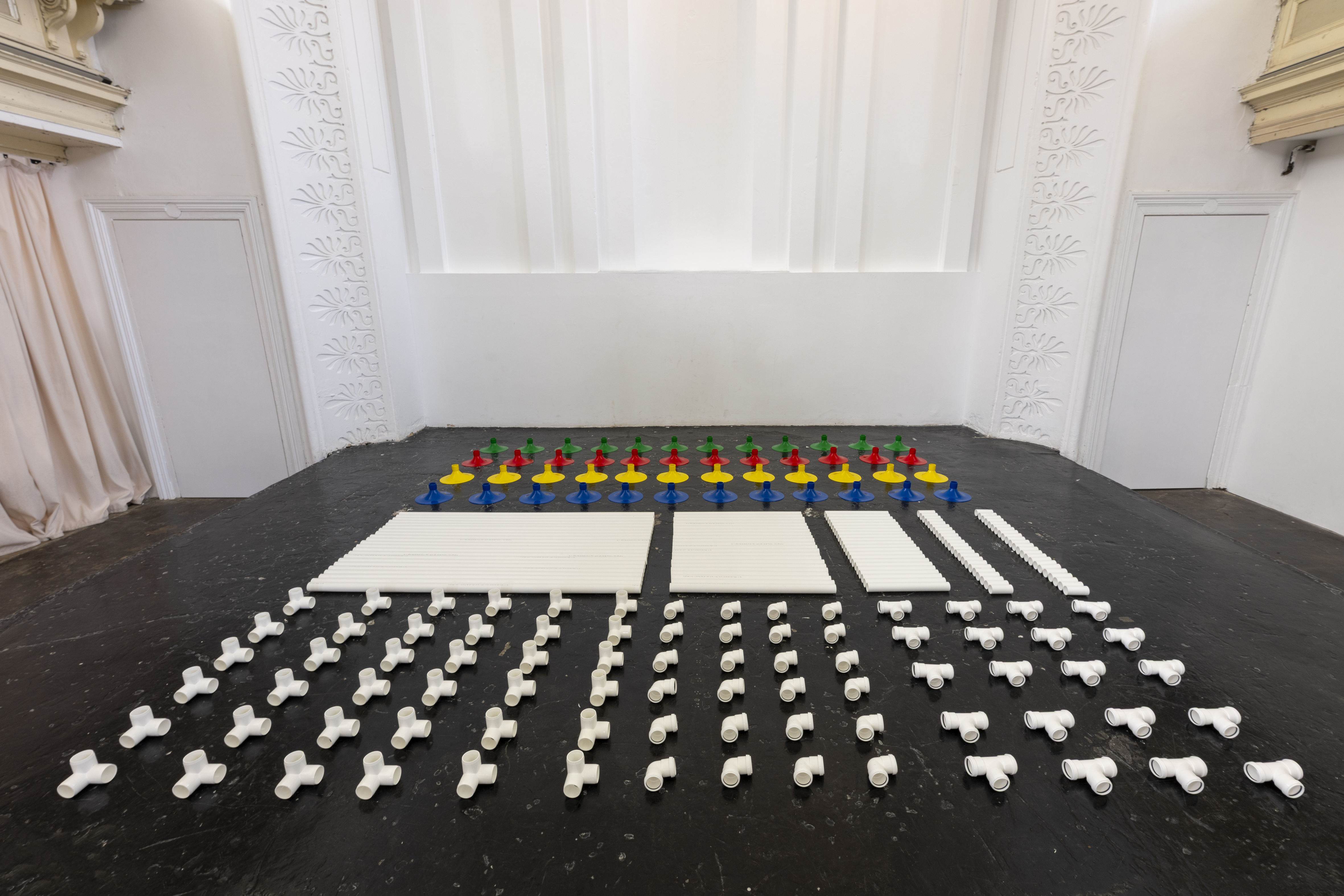 Installation in a former church made out of white pipes and colourful funnels