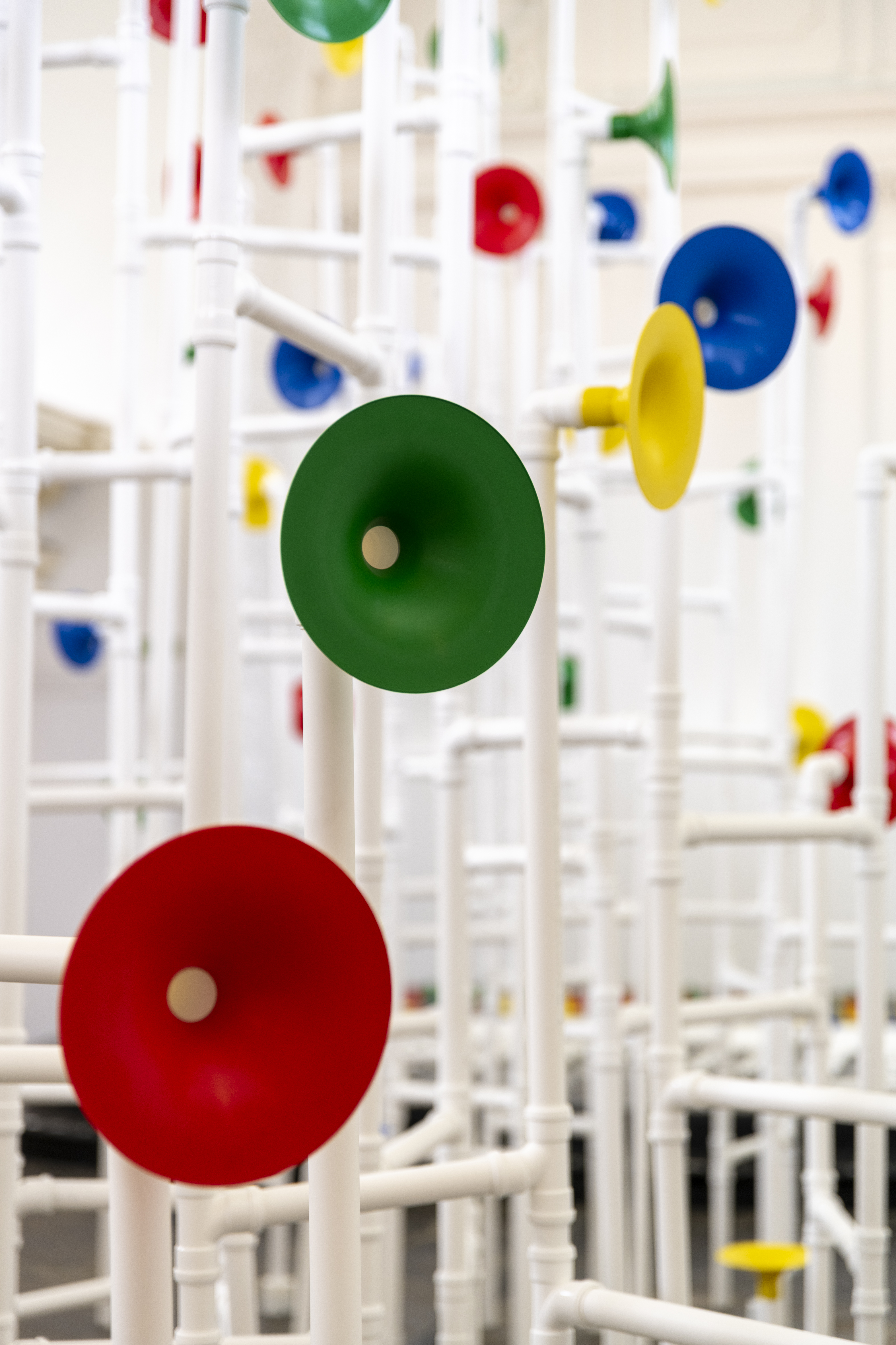 Installation in a former church made out of white pipes and colourful funnels
