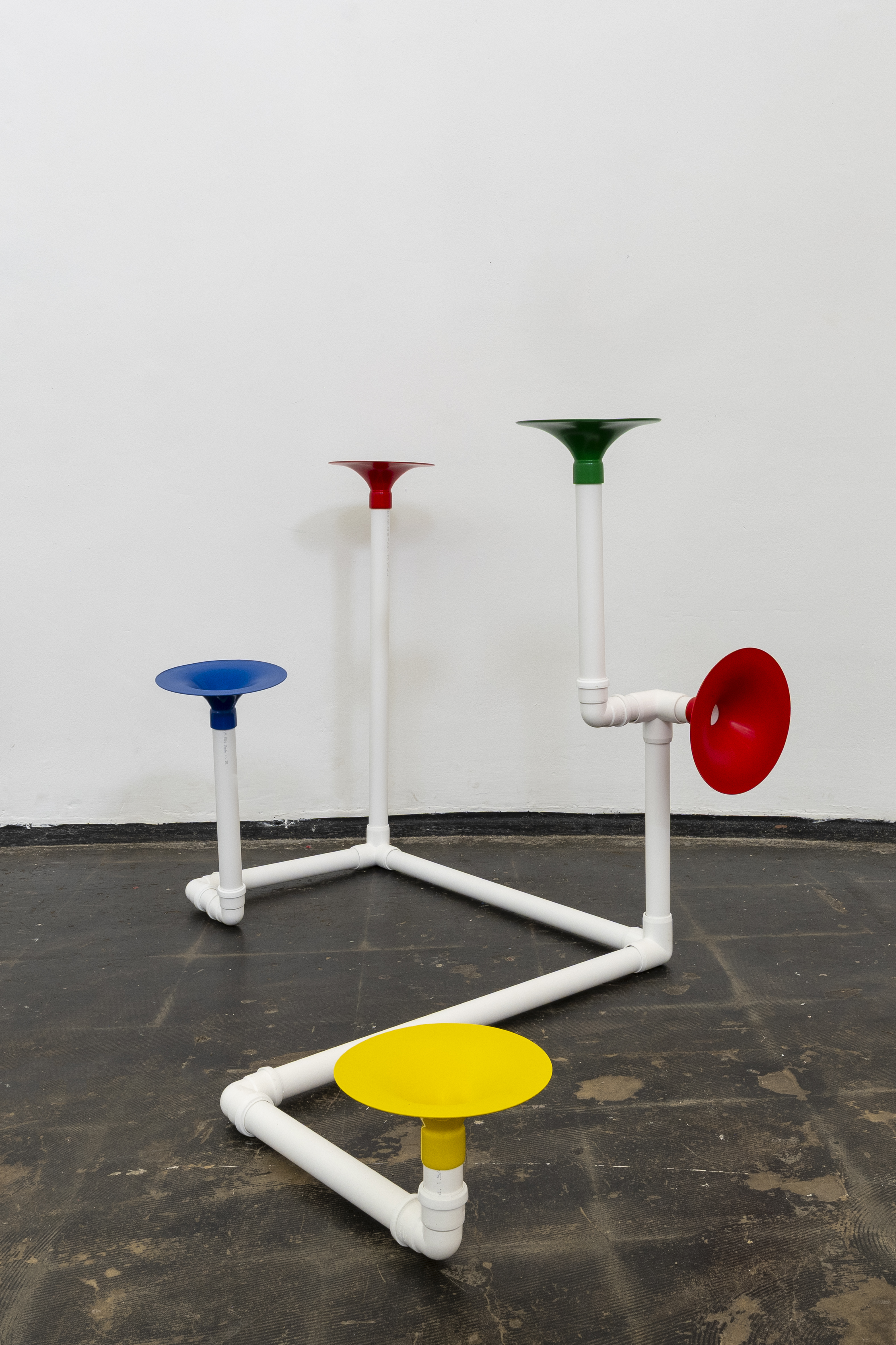 Installation in a former church made out of white pipes and colourful funnels