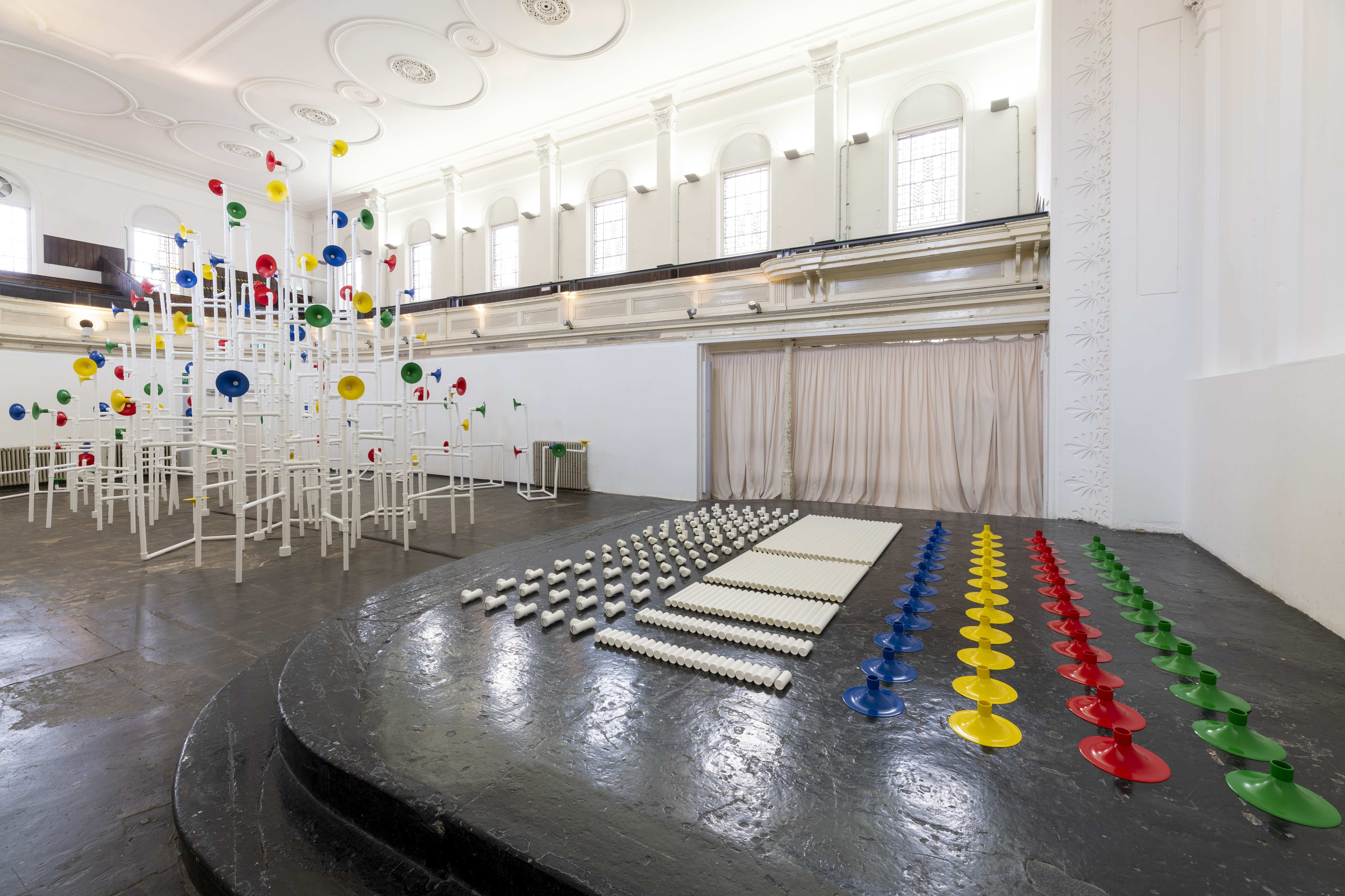 Installation in a former church made out of white pipes and colourful funnels