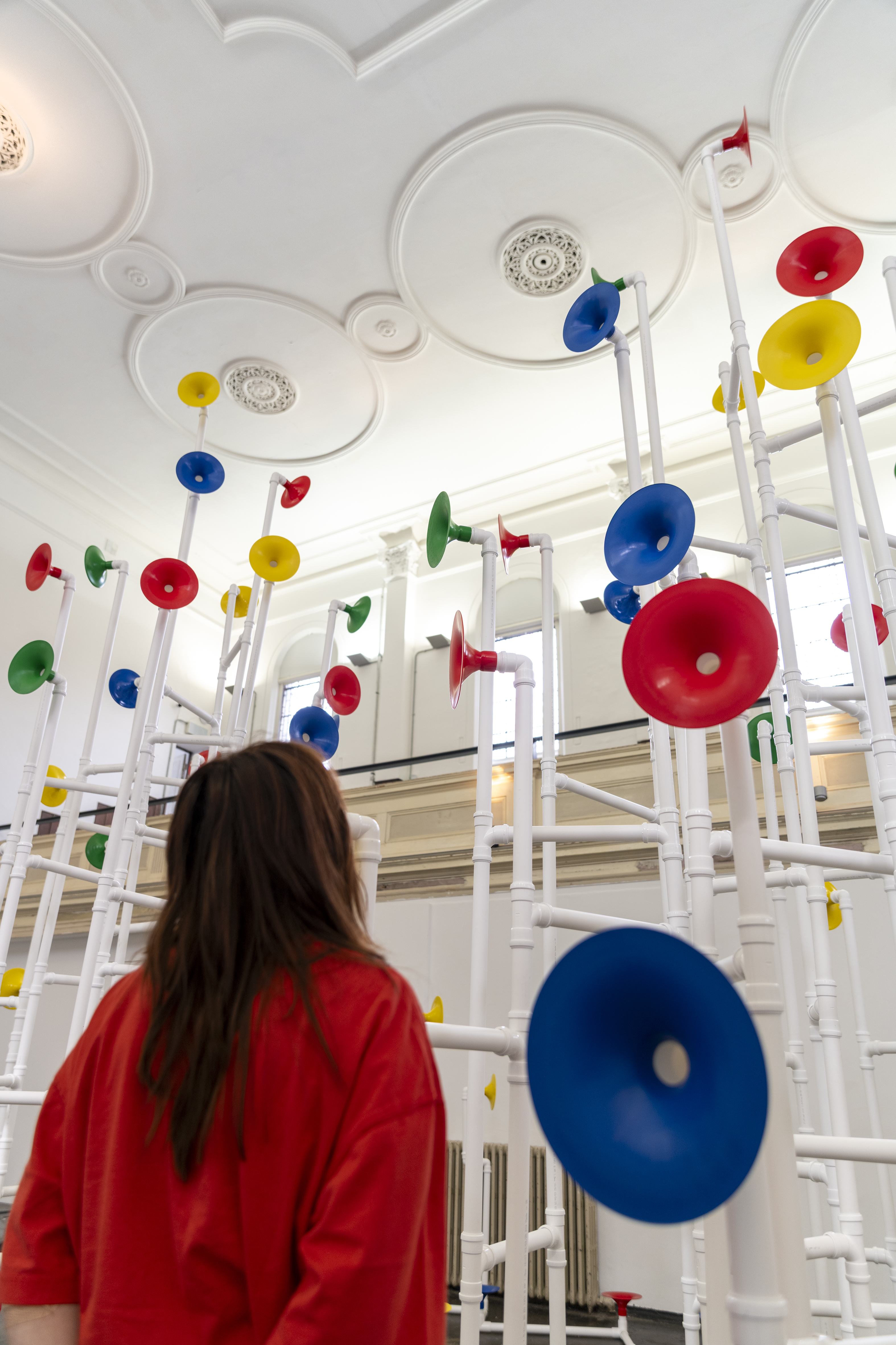 Installation in a former church made out of white pipes and colourful funnels