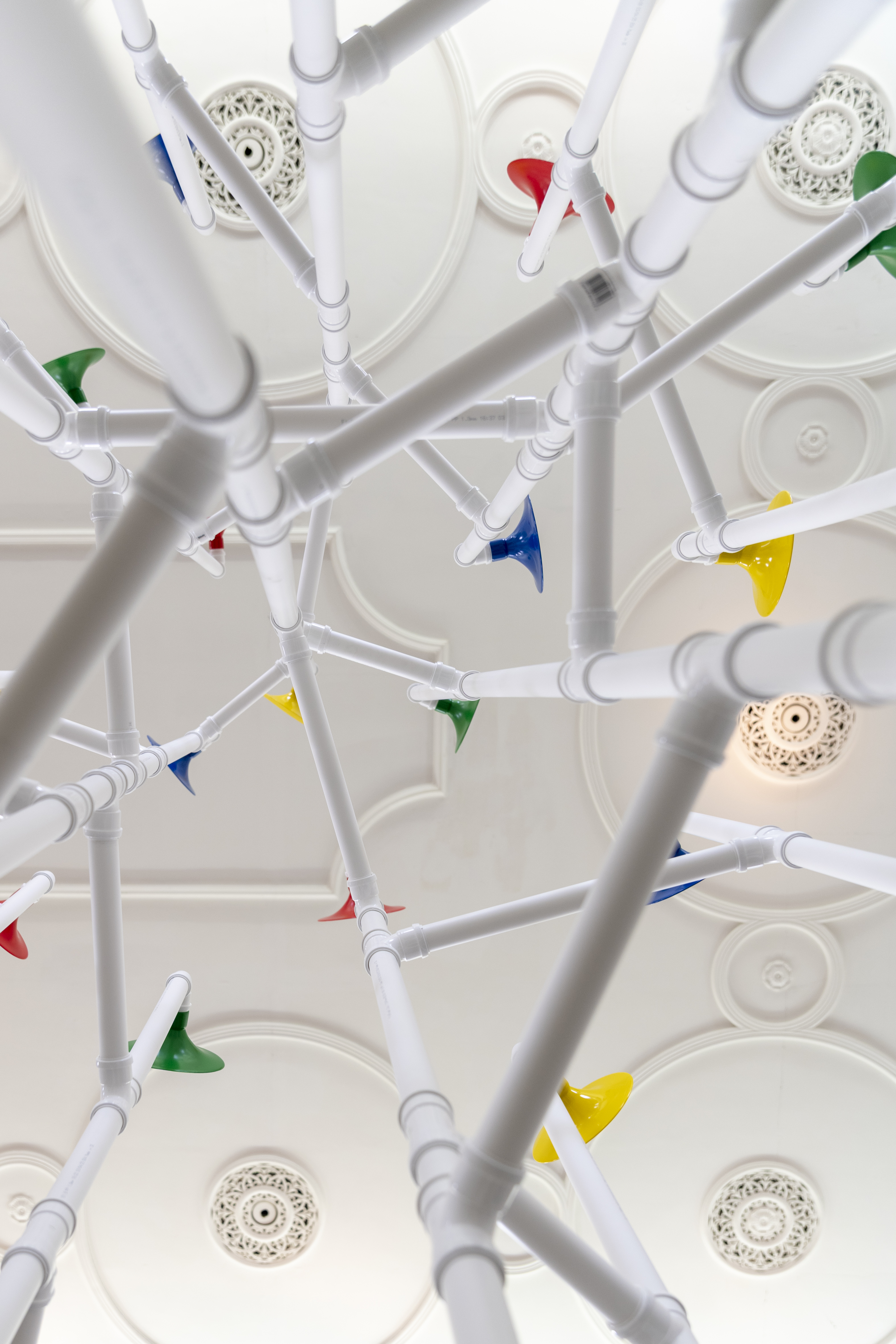 Installation in a former church made out of white pipes and colourful funnels