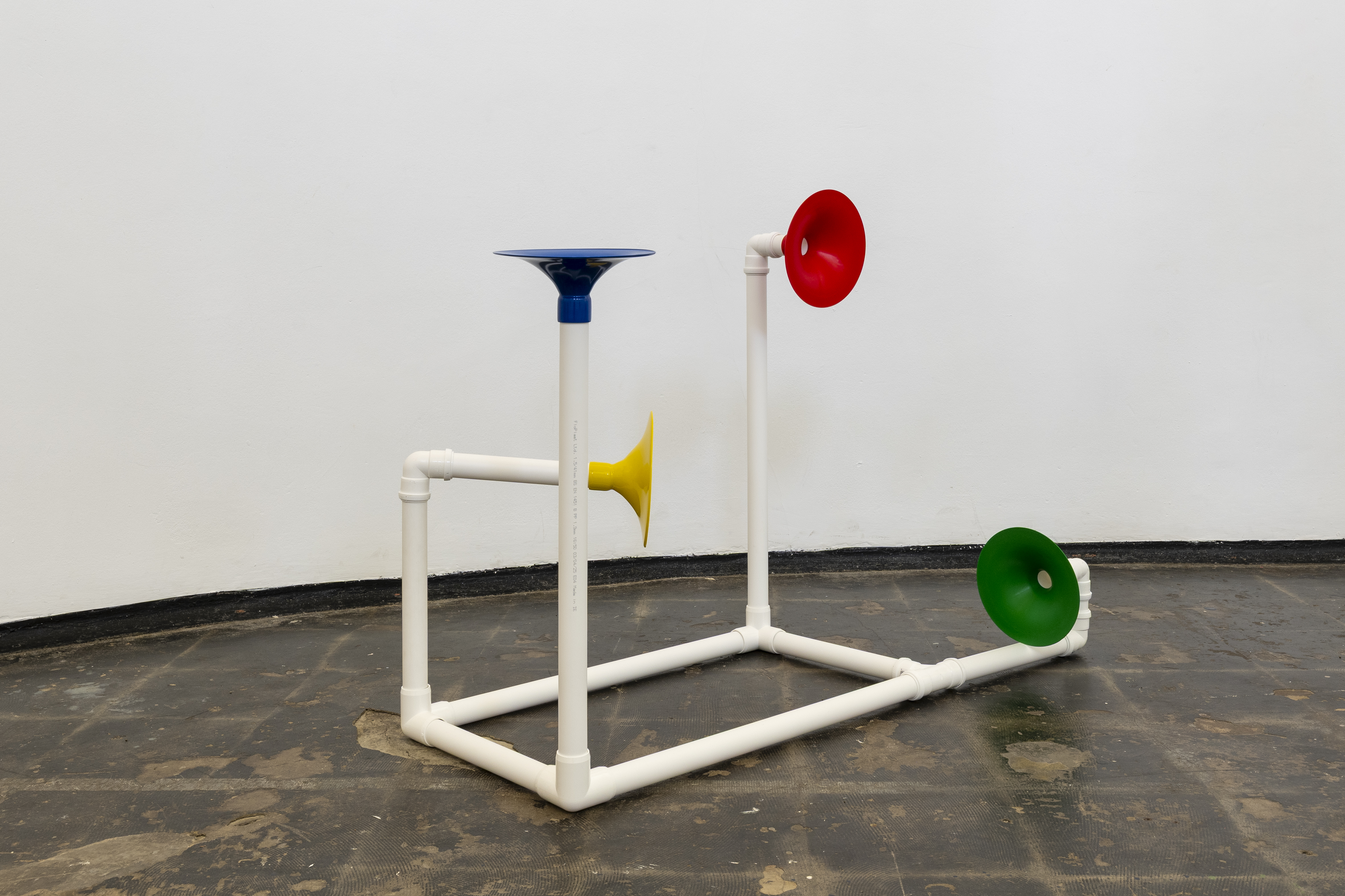 Installation in a former church made out of white pipes and colourful funnels