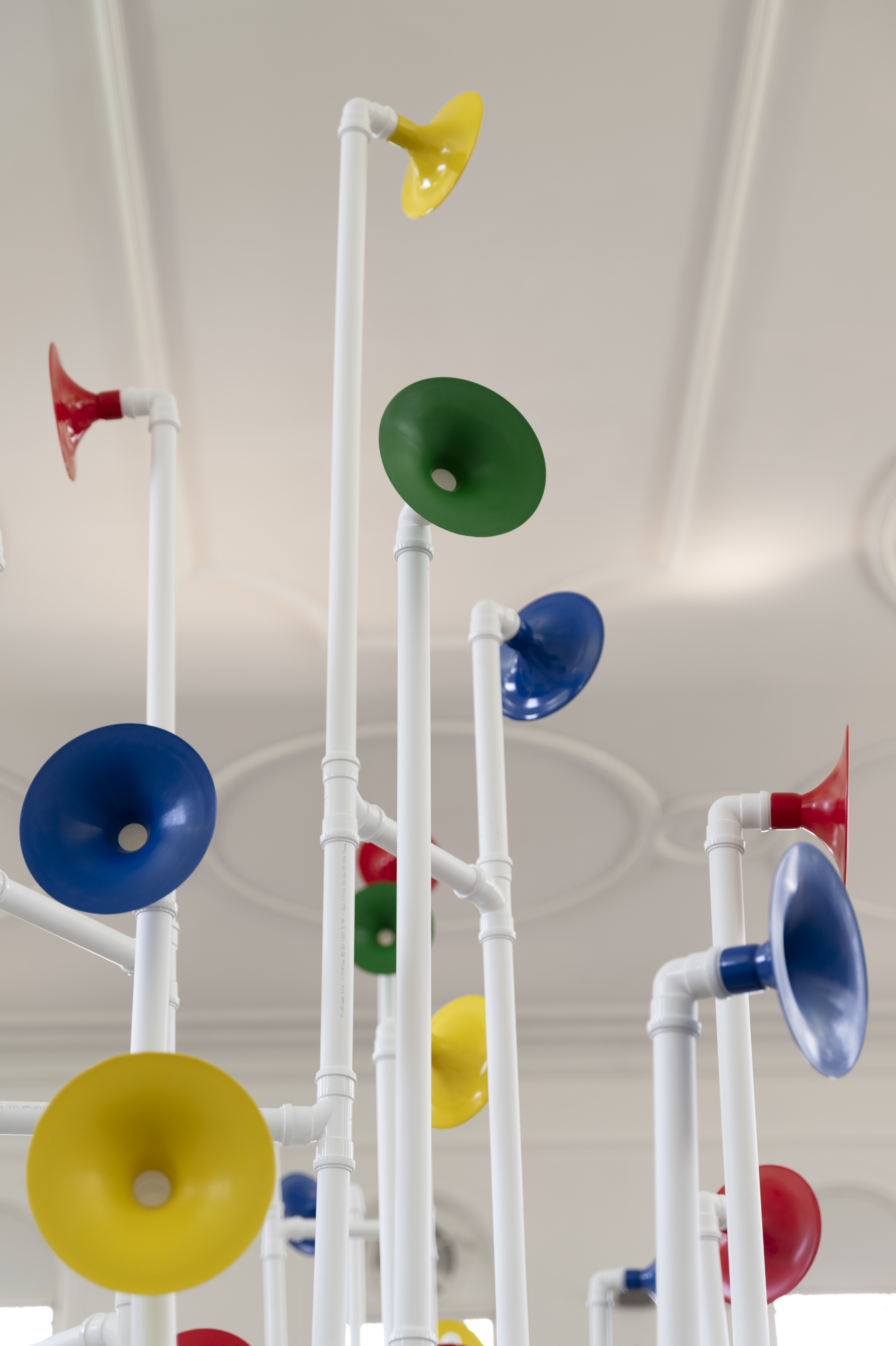 Installation in a former church made out of white pipes and colourful funnels