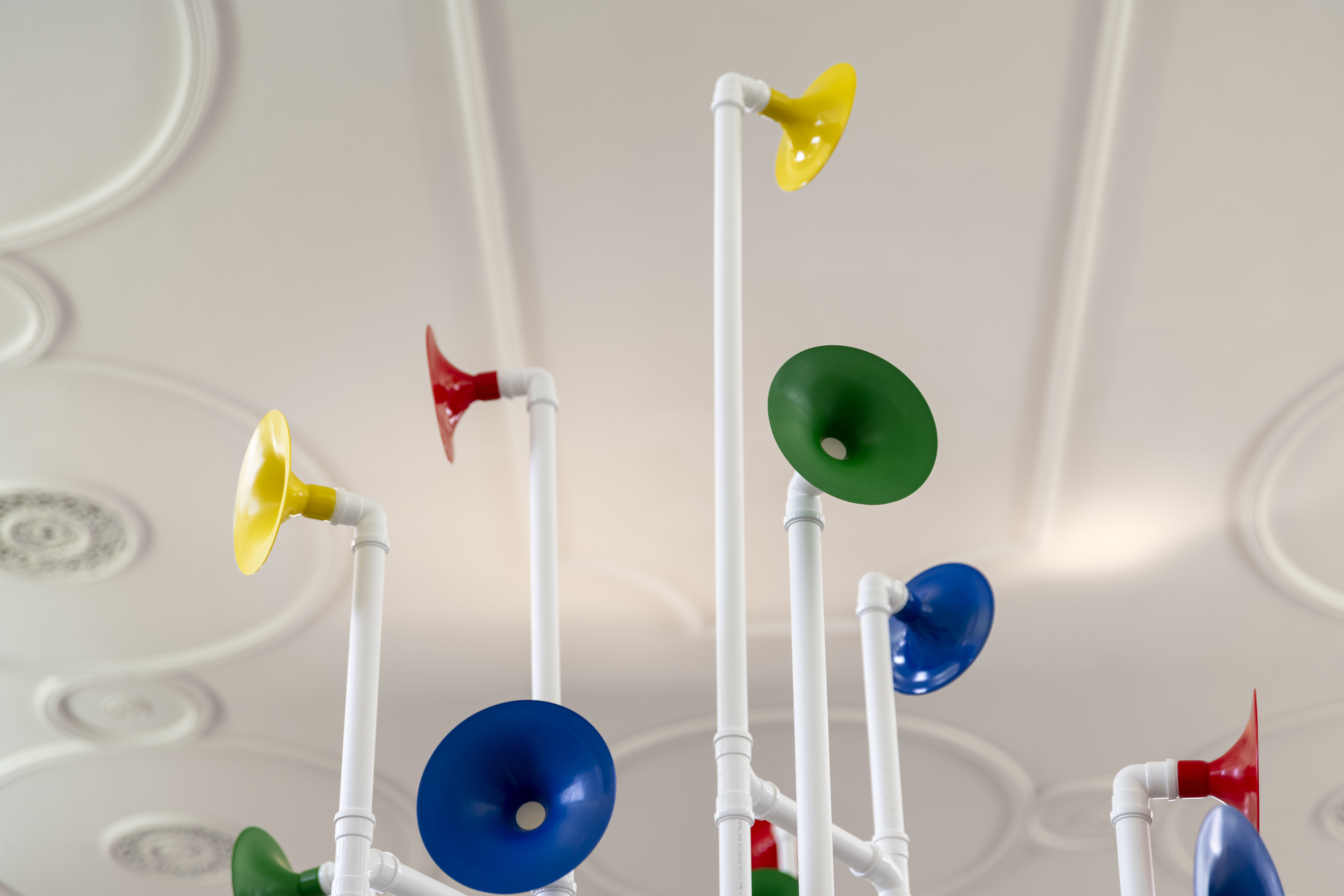 Installation in a former church made out of white pipes and colourful funnels