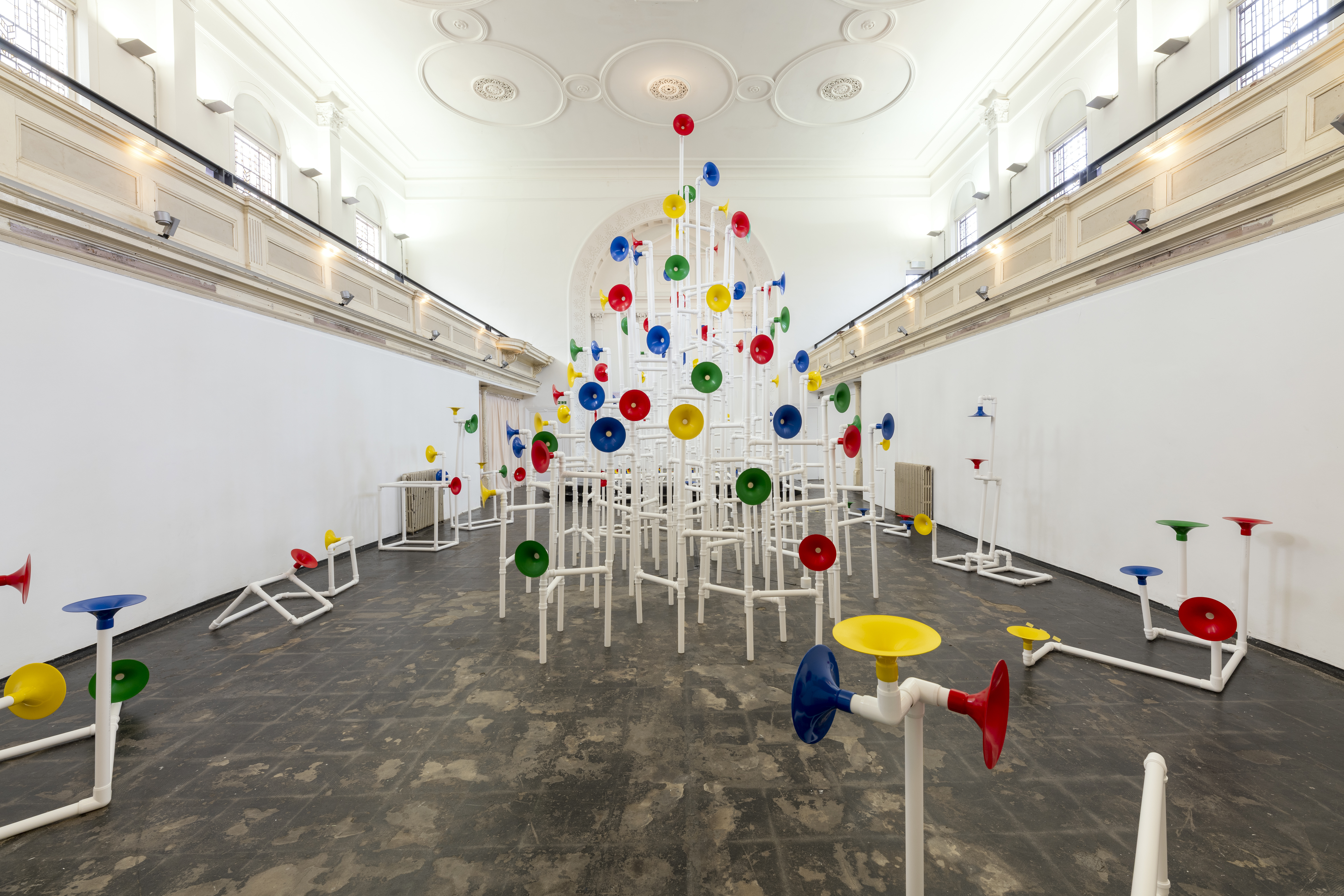 Installation in a former church made out of white pipes and colourful funnels