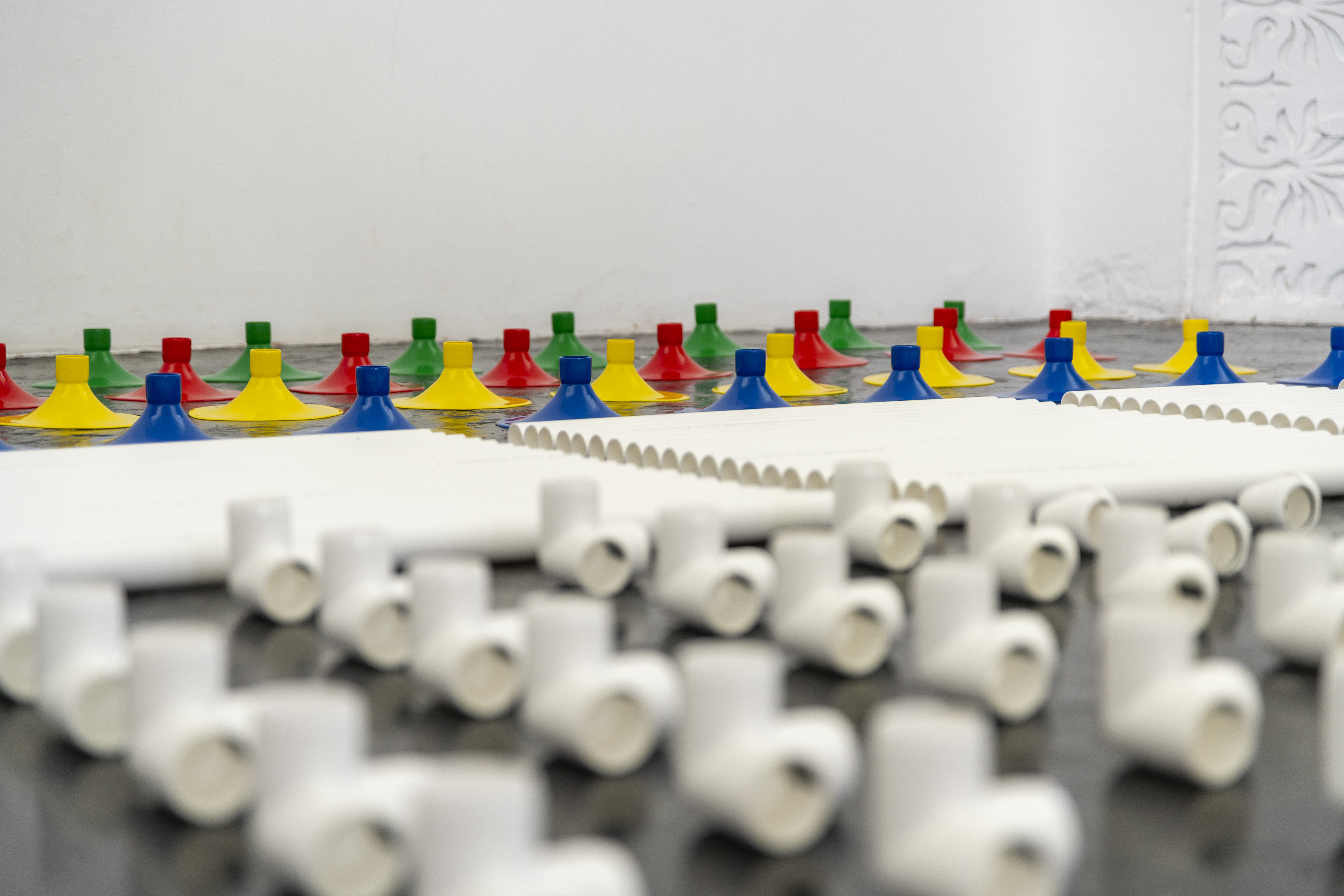 Installation in a former church made out of white pipes and colourful funnels