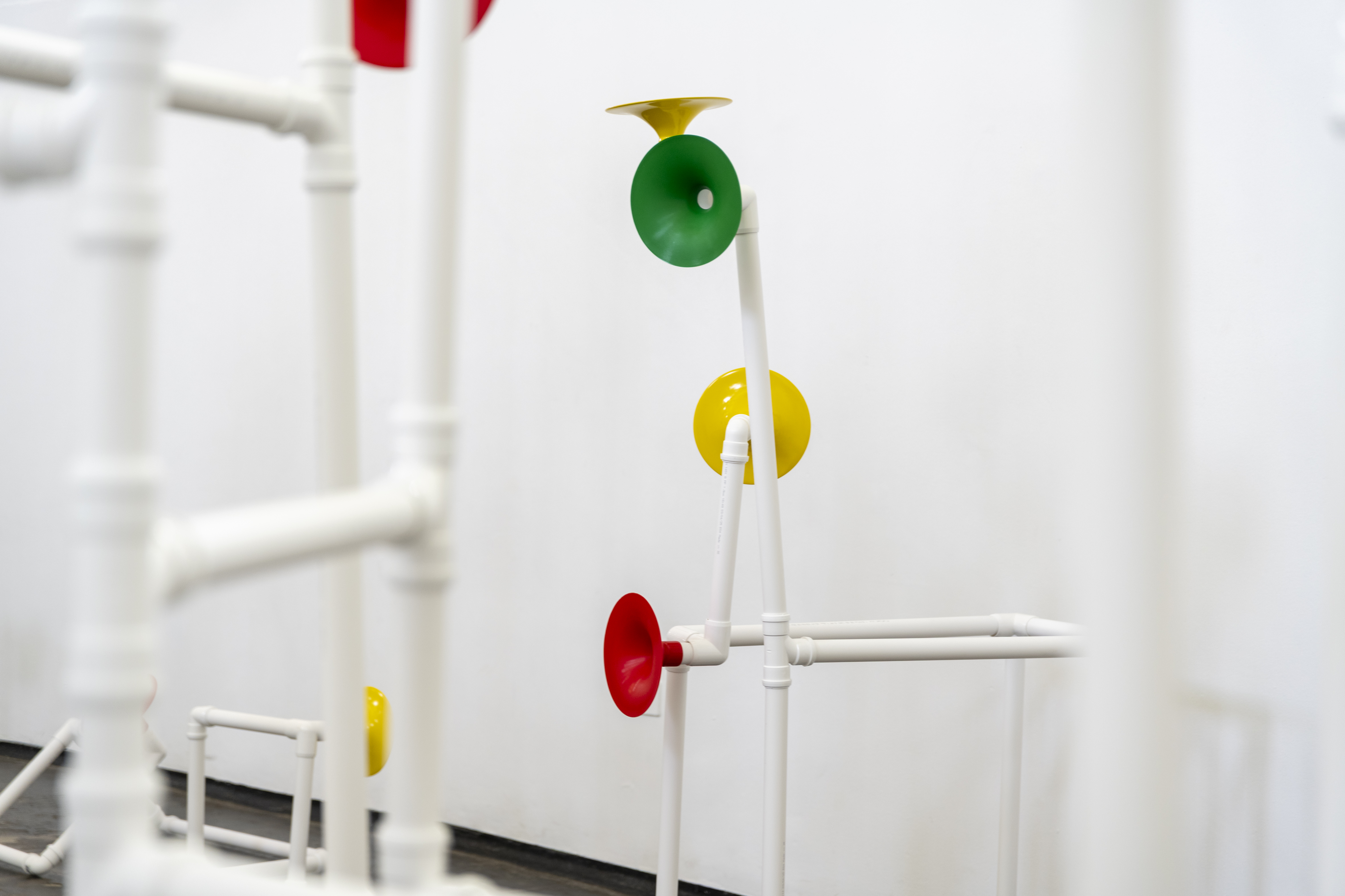 Installation in a former church made out of white pipes and colourful funnels
