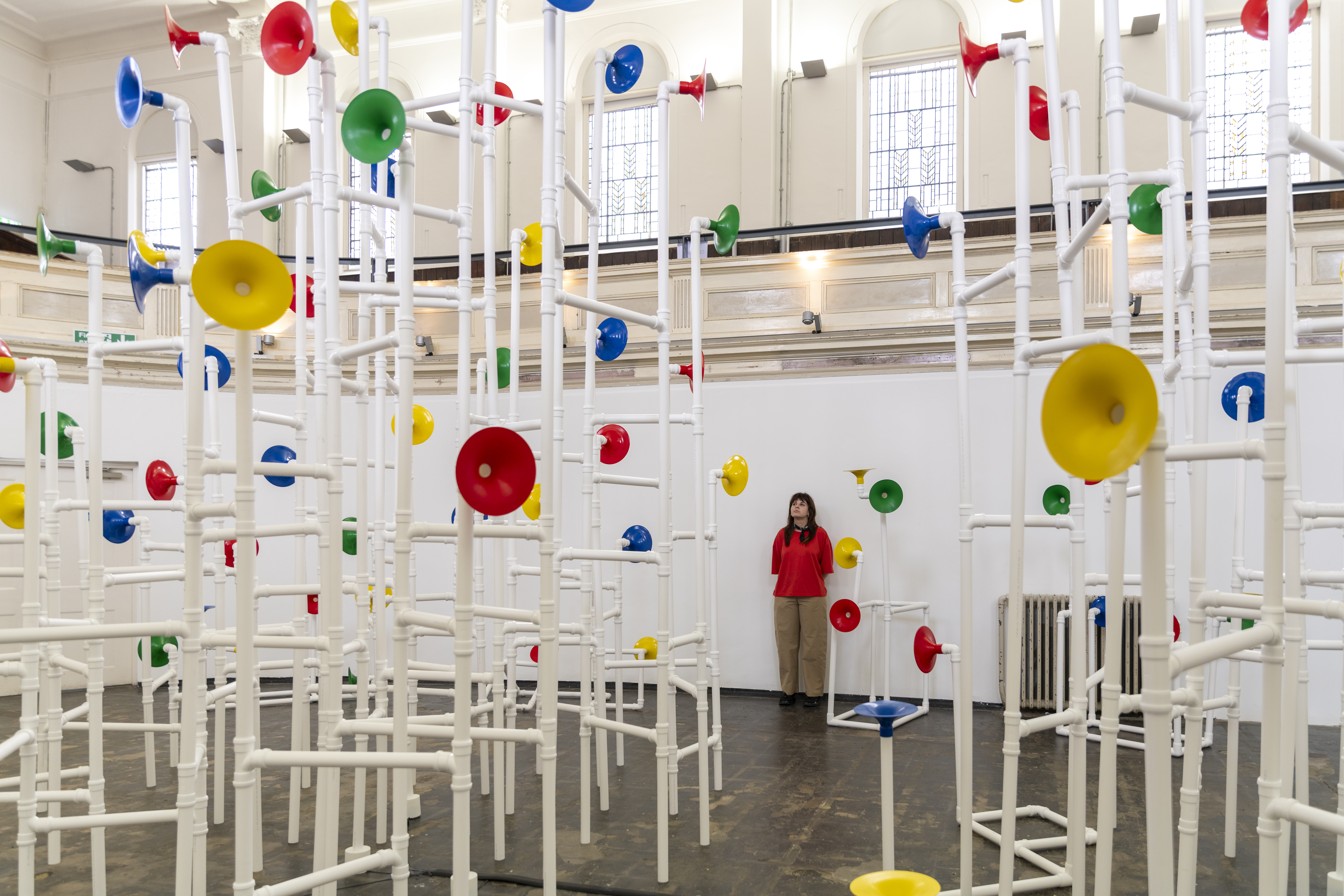 Installation in a former church made out of white pipes and colourful funnels