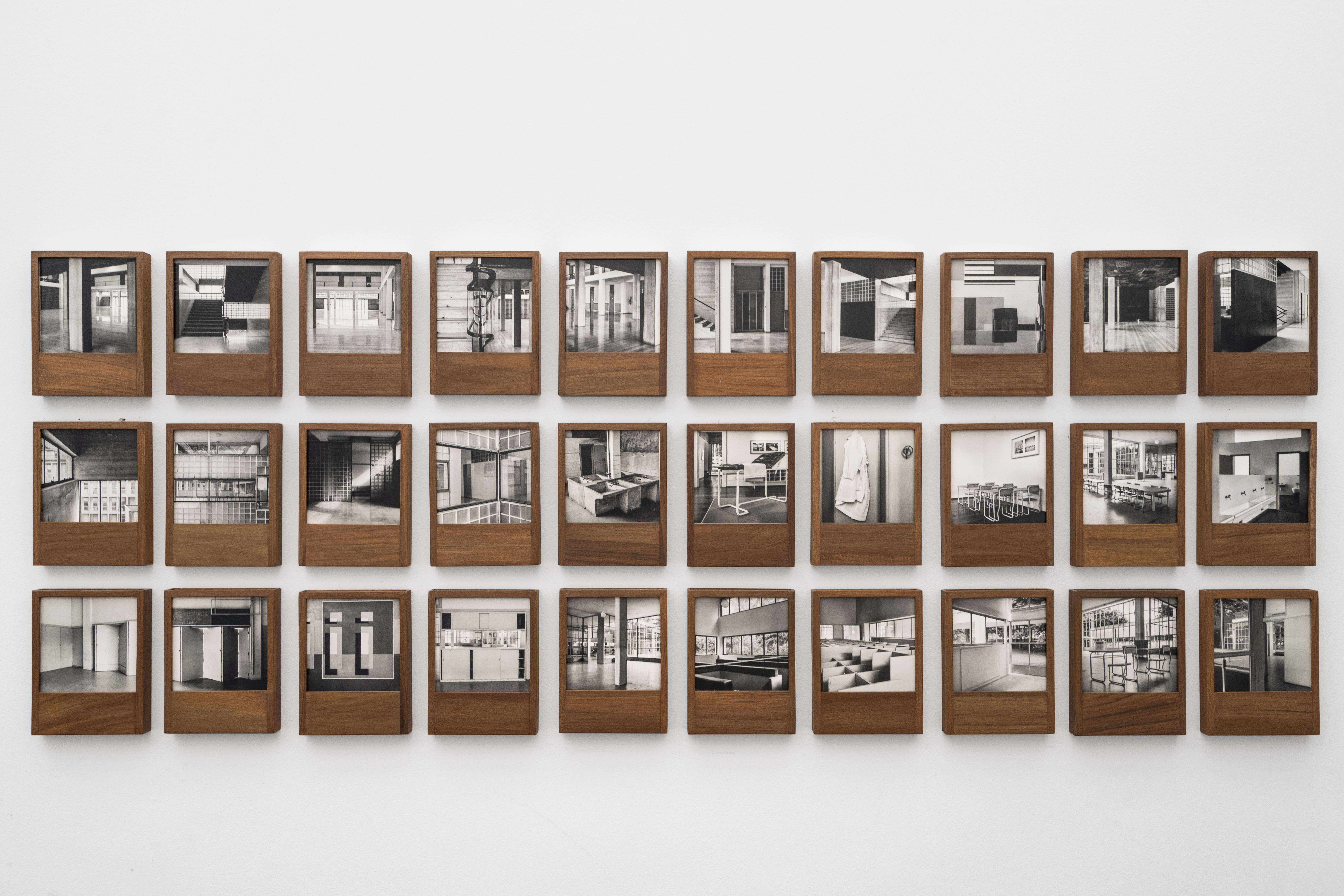 Wall of black and white images framed in wood