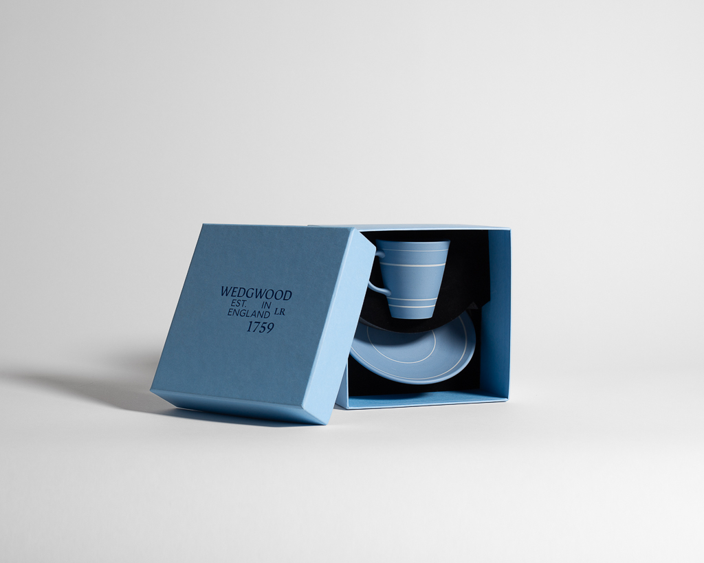 Blue cup with white horizontal lines, resting on round plate with a white line around its edge