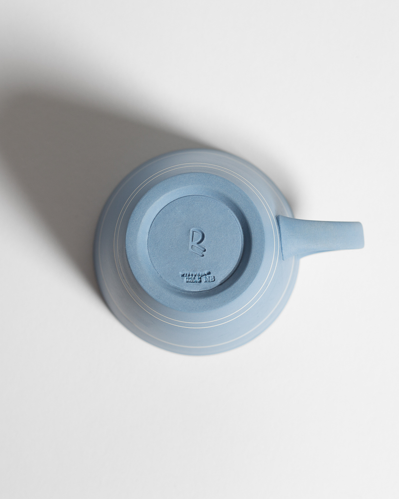 Blue cups with white horizontal lines, resting on blue plates with white lines around the border
