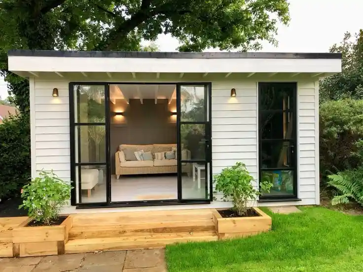 A white paneled outhouse sunroom with large windows