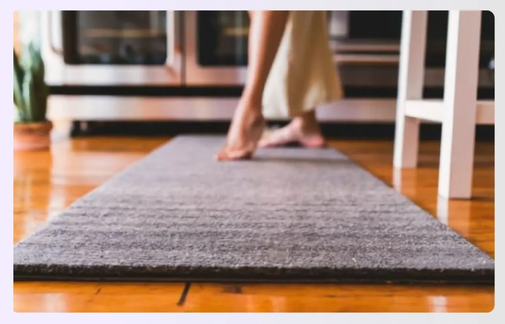 A grey water-absorbent bar mat on wood floor