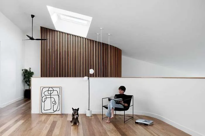Close-up of a curved timber batten wall on the mezzanine level of a modern barn style home.