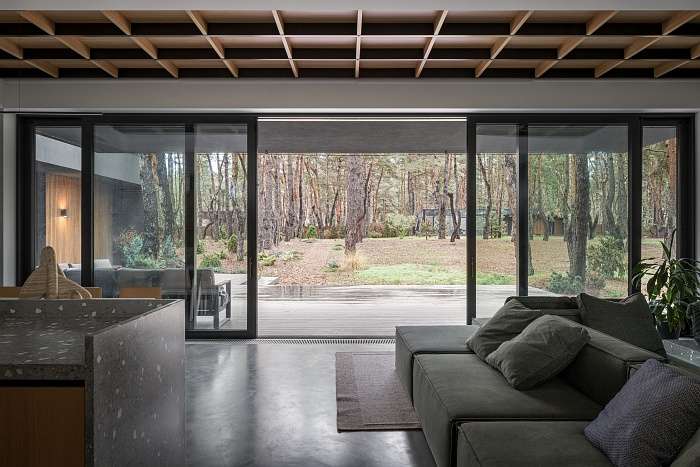 Living room with low sectional sofa and panoramic big glazing blending interior space