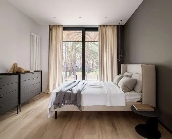 Upstairs bedroom with neutral tones, wide glazing, and views of the surrounding forest canopy.
