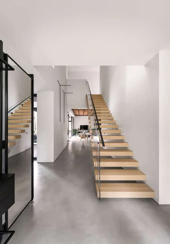 Minimal interior with open-riser wooden staircase connecting levels in a modern house with inner courtyard.