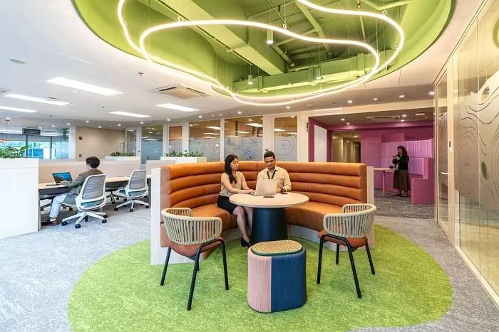 Collaborative hub with circular green carpet and sculptural ceiling feature in a modern organic interior design.