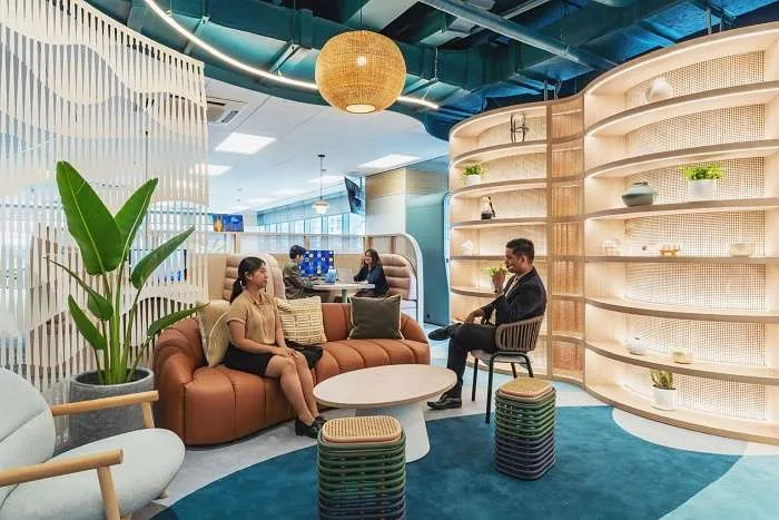 Collaborative lounge area with rattan-inspired shelving and curved seating in a modern organic office.