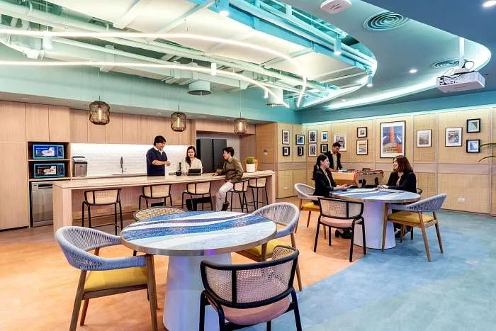 Open work café with round tables, curved ceiling lines, and flexible seating in a modern organic office.