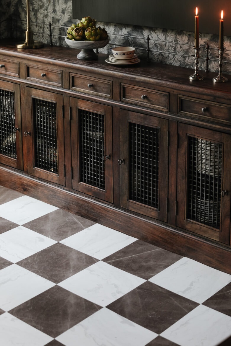 A vintage wooden sideboard with decorative items next to a bronze & white marble-look peel-and-stick floor.